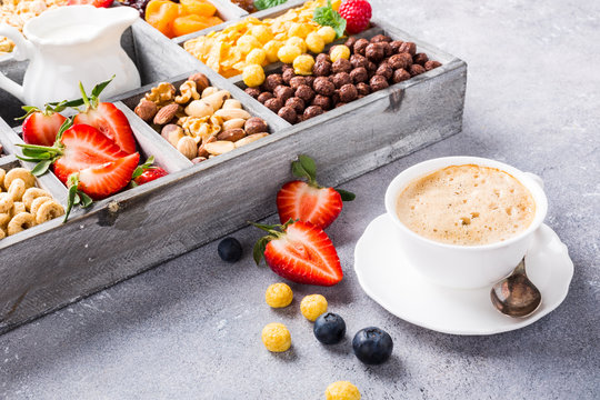 Healthy breakfast with coffee, variety of cold quick cereals and berries in old gray wooden box, selective focus.