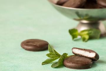  Dessert. Chocolate sweets with mint flavor and fresh mint leaves on a light background.