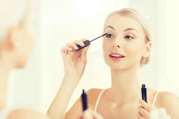woman with mascara applying make up at bathroom