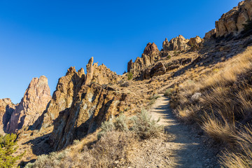 The path among the rocks. The sheer rock walls. Beautiful landscape of yellow sharp cliffs. Dry yellow grass grows on the slopes of the mountains.  BURMA ROAD TRAIL, Smith Rock State Park