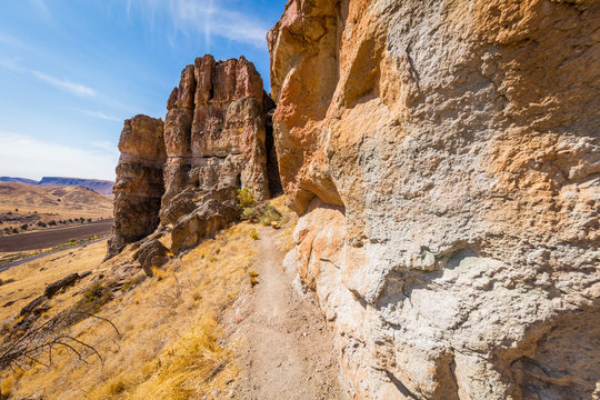 The path among the rocks. The sheer rock walls. Beautiful landscape of yellow sharp cliffs. Dry yellow grass grows on the slopes of the mountains. John Day Fossil Beds 