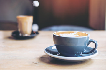 Two cups of hot coffee on wooden table in vintage cafe