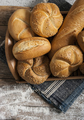 Bread and lots of fresh bread buns in a basket on a wooden table