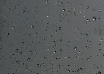Rain drops, water drops of rain on a window glass with blurred dark background