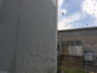 Rain drops, water drops of rain on a window glass with blurred building and road