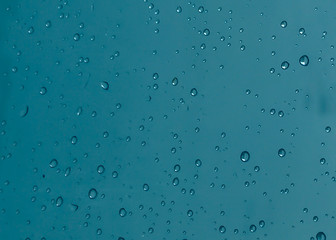 Rain drops, water drops of rain on a window glass with blurred dark blue background