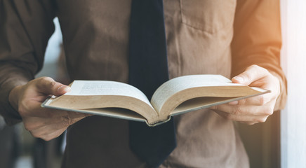 Businessman standing near window and reading book vintage tone.