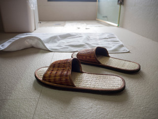 Slippers on the floor in the bathroom the back is a white cloth put in front of the shower