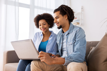 smiling happy couple with laptop at home