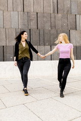 Two young women holding up the hand and walk around. Urban concept