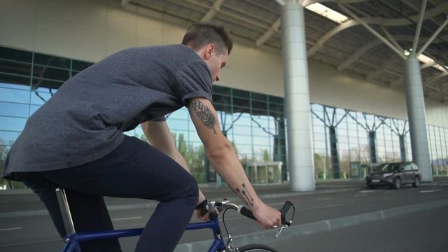 Handsome tattoed man riding his bike near the airport slow motion