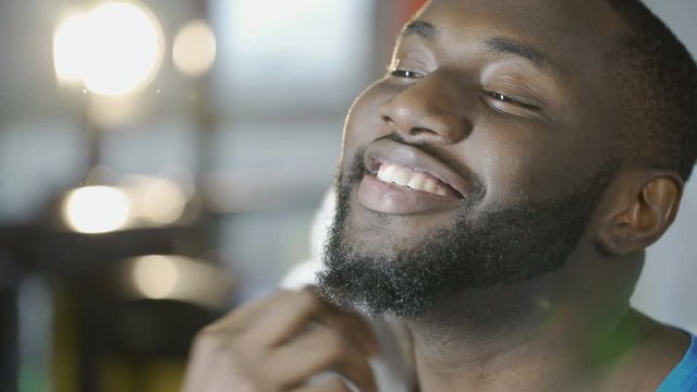 Happy handsome man smiling, touching beard, satisfied with barbershop services