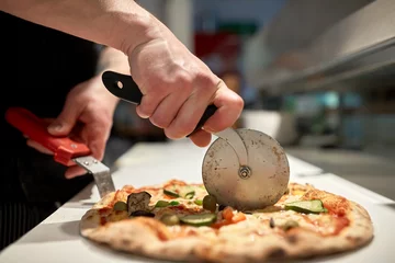 Zelfklevend Fotobehang kook pizza in stukjes snijden bij pizzeria © Syda Productions