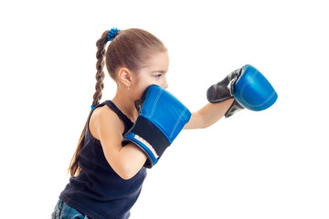 the little child is standing sideways in front of the camera and reaches out his hands in boxing gloves