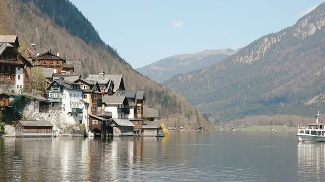 The composition of the swimming boat near the little town placed on the bank in the mountains.