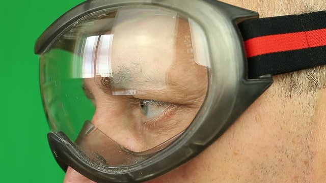 Adult caucasian man in protective eyeglasses profile. Extreem close-up view of male face in glasses. Worker in goggles in profile. A scientist with glasses. Skier or biker. Eyes and glasses close up