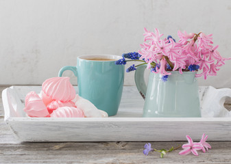 A cup of coffee and a bouquet of flowers on a wooden table