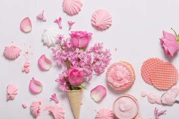 Flowers in a waffle cone with yogurt and meringues on white background