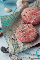 Organic raw ground beef wrapped in strips of bacon.