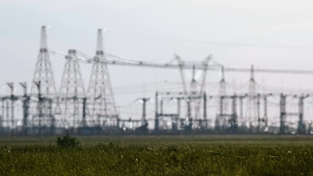 Wide shot of two engineers in hard hat discussing something talking on a smartphone during an energy substation inspection.