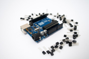 Arduino and around transistors lined up on a white background