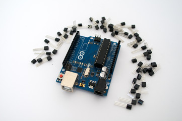 Arduino and around transistors lined up on a white background