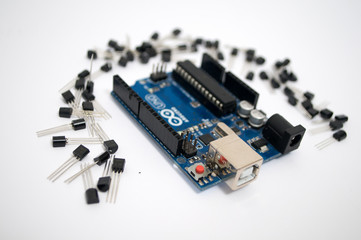 Arduino and around transistors lined up on a white background