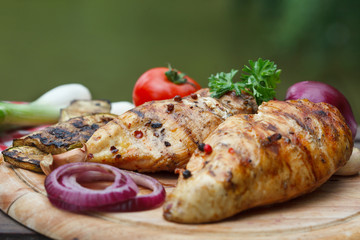 Roasted chicken breast and various vegetables on a chopping wood