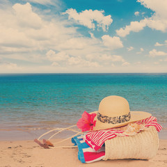 sunbathing accessories on beach in straw bag, summer relaxation and vacations concept, retro toned
