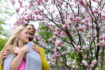 romantic couple in love in spring garden at blooming magnolia