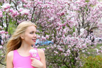 young beautiful woman near magnolia tree with flowers