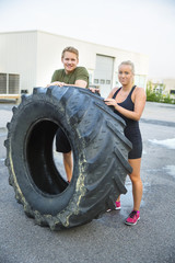 Fototapeta na wymiar Confident Athletes Standing By Huge Tire Outside Health Club