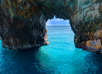 Beautiful view on rock arces arches of Blue caves from sightseeing boat with tourists in blue water of Ionian Sea inside cave, Island Zakynthos, Greece holidays vacation. Trip from Agios Nikolaos port