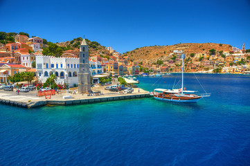 View on Greek sea Simy island harbor port, classical ship yachts, houses on island hills, tourists Aegean Sea bay. Greece islands holidays vacation travel tours from Rhodos island. Greece architecture - obrazy, fototapety, plakaty