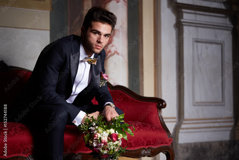 Wall mural young groom waiting his bride on sofa