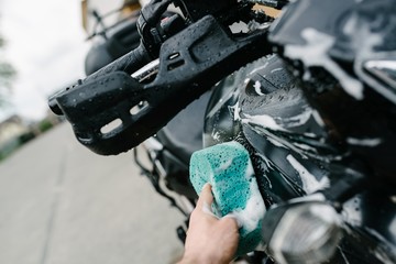 Cleaning black touristic motorbike with water