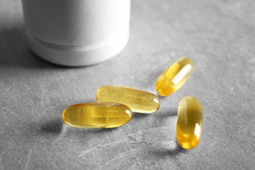 Fish oil capsules on textured background, close up