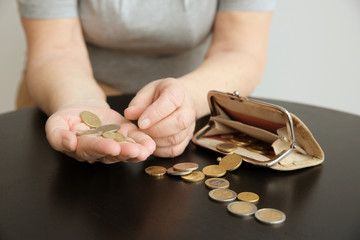 Senior woman counting coins while sitting at table, closeup. Poverty concept