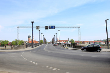 Cars crossing bridge. Traffic sign on crossroad with the bridge.