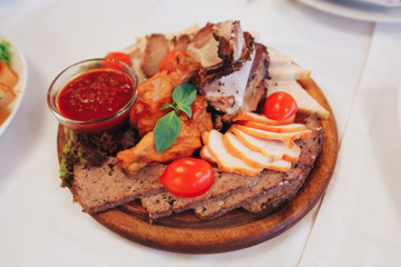 grilled meat of different kinds, fresh red tomato ketchup sauce, thyme seasoning, on a wooden tray