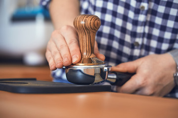 Female barista tamping fresh ground coffee