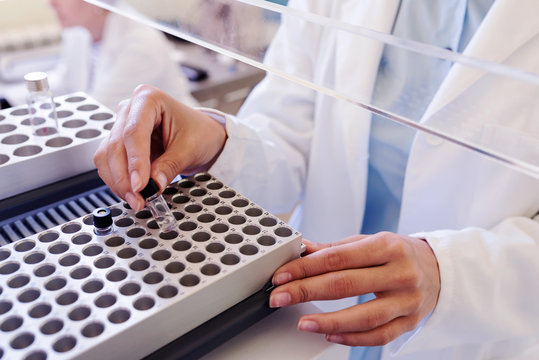 Scientist putting samples in research equipment. Scientist carrying out experiment in research laboratory.