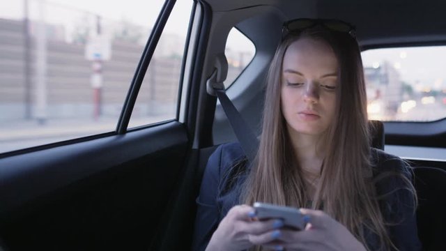 Young Businesswoman Holding a Mobile Phone in the Car
