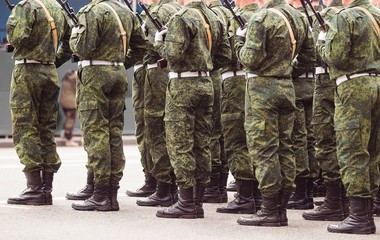 Soldiers in green uniforms stand at attention