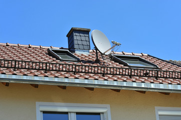 Mit Naturschiefer-Schindeln verkleideter Schornstein auf einem Ziegeldach