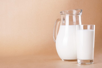 Milk in a jar and a glass on a beige background
