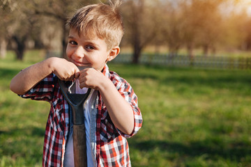 Smiling chestnut haired boy with spade in garden
