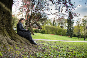 Fototapeta premium woman wokring on laptop in the park under the tree