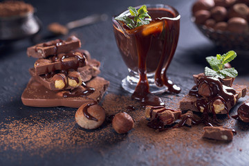Homemade hazelnut spread or hot chocolate in glass bowl with nuts and chocolate bar.