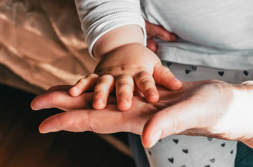 The hand of the baby touches the palm of the grandmother.